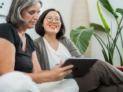 Zwei Mitarbeitende sitzen auf Sofa und besprechen Design auf Tablet